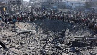فلسطينيون يتجمعون حول حفرة كبيرة في أعقاب غارة إسرائيلية على حي الزيتون