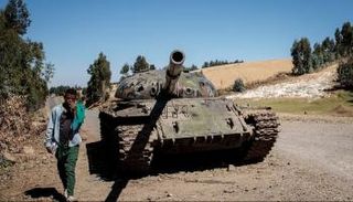 شاب إثيوبي يمر إلى جانب دبابة بإقليم تيغراي - أرشيفية
