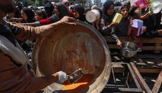 حشد من الفلسطينيين المحاصرين بغزة يتجمعون حول نقطة توزيع وجبات