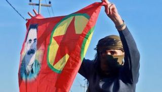 أحد عناصر حزب العمال الكردستاني يرفع صورة لأوجلان