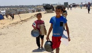 أطفال فلسطينيون نازحون يحملون أوانٍ فارغة في خان يونس 