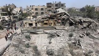 فلسطينيون يتفقدون أنقاض منزل في حي التفاح بغزة