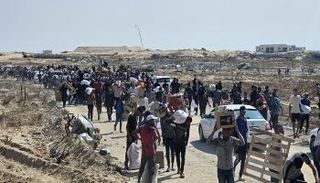 يسير فلسطينيون نازحون على طول الطريق لتلقي طرود مساعدات إنسانية في رفح