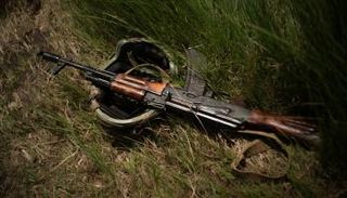 خوذة عسكرية وبندقية على الأرض خلال تدريب جنود أوكران