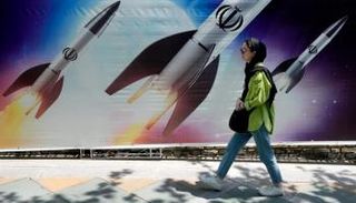 فتاة إيرانية تسير أمام جدارية في طهران- أرشيفية