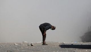 فلسطيني يفحص نفسه بحثًا عن جروح بينما يتصاعد الدخان بعد غارة إسرائيلية