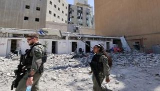 جنود إسرائيليون يسيرون وسط الأنقاض خارج مستشفى سوروكا في مدينة بئر السبع 