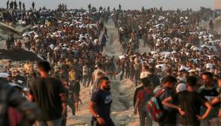 فلسطينيون يحملون أكياس الدقيق على طول شارع الرشيد غرب جباليا