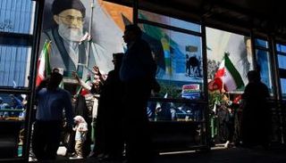 متظاهرون يسيرون تحت جدارية للمرشد الأعلى الإيراني علي خامنئي،