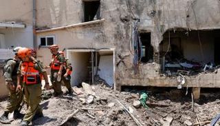 جنود إسرائيليون يتفقدون الأضرار التي لحقت بمبنى جراء غارة إيرانية