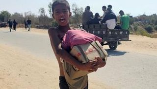 صبي في رفح يمشي حاملاً طرود إغاثة إنسانية  