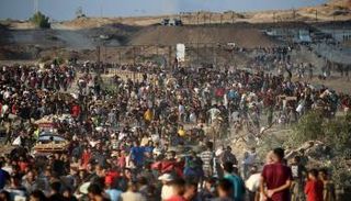 فلسطينيون يتجمعون عند نقطة توزيع مساعدات قرب مخيم النصيرات بغزة