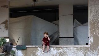  طفل يجلس في شرفة عقب استهداف خيام النازحين شمال مدينة غزة