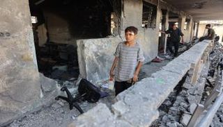 طفل يتفقد آثار الدمار في مدرسة تؤوي نازحين بعد غارة إسرائيلية ليلية على غزة