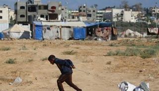 صبي يسحب بعض النفايات من مكب بمخيم البريج