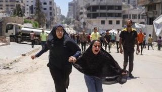 فتاتان تهرولان بأحد الشوارع عقب غارة إسرائيلية