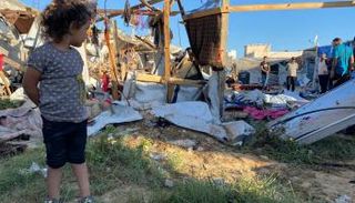 طفلة فلسطينية تنظر للدمار في مخيم للنازحين بخان يونس