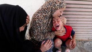 أم تحتضن طفلها أمام مستشفى شهداء الأقصى وسط القطاع