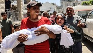 شاب يحمل جثمان طفل قُتل في غارة إسرائيلية