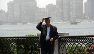 رجل يحتمي من حرارة الشمس في وسط القاهرة