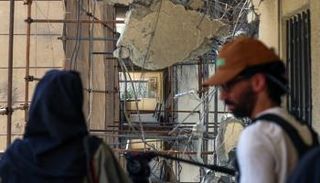 شاب وفتاة في إيران أمام مبنى متضرر جراء القصف الإسرائيلي