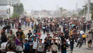 فلسطينيون يسيرون في شارع الرشيد غرب جباليا