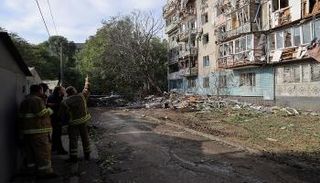 رجال إنقاذ أوكرانيون يتفقدون مبنى سكنيًا متضررًا إثر هجوم بطائرة مسيرة في أوديسا