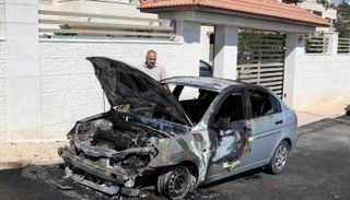 رجل يتفقد سيارة قيل إن مستوطنين إسرائيليين أحرقوها 