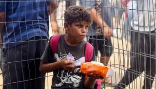 طفل فلسطيني يحمل كيسا من الطحين في غزة - أ.ف.ب