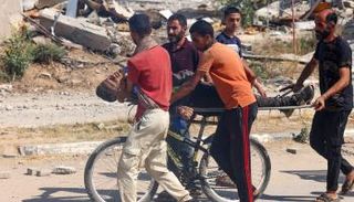 فلسطينيون يحملون جثمان قتيل على دراجة