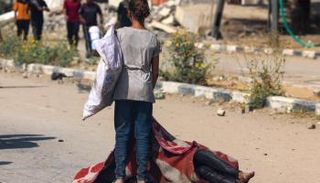 فتاة تقف بجانب جثة شخص قُتل أثناء بحثه عن الطعام بغزة