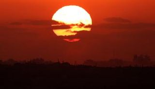 الشمس تغرب خلف مبان مدمرة في قطاع غزة