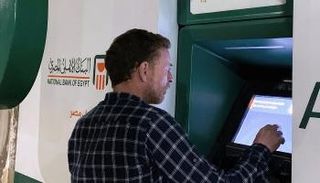 شخص سقف أمام ماكينة تابعة للبنك الأهلي المصري - رويترز