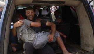 فلسطيني يحمل طفلا مصابا في غزة