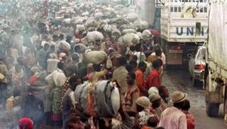 شاحنات أممية تمر إلى جانب نازحين في رواندا - أرشيفية