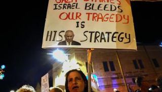 متظاهرة ترفع لافتة مناهضة للحكومة أمام السفارة الأمريكية في القدس