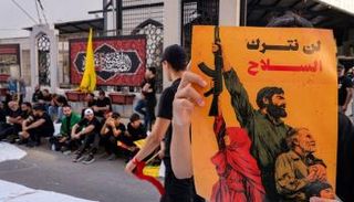 أحد عناصر حزب الله يحمل لافتة كُتب عليها «لن نتخلى عن السلاح»