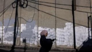 فلسطينية عند الجدار العازل في قرية أبوديس الفلسطينية