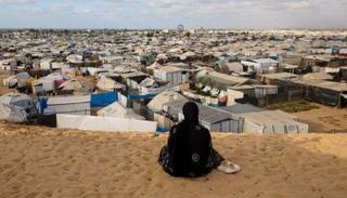 امرأة تنظر إلى معسكر خيام في غزة