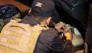 عنصر أمني يفتش سيارة