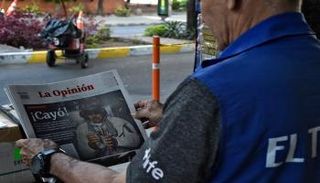 ينظر رجل للصفحة الأولى من صحيفة تحمل صورة للرئيس الفنزويلي مادورو