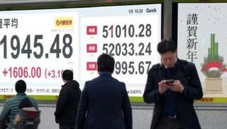 يابانيون يمرون أمام شاشة لعرض الأسهم في طوكيو