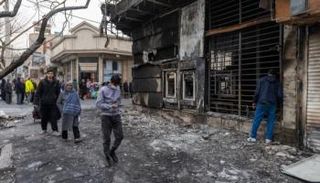 شاب يمر بجوار مبنى تدمر في الاحتجاجات