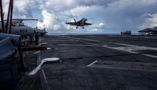 مقاتلة تستعد للهبوط على سطح حاملة طائرات أمريكية