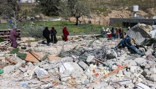 فلسطينيون بجوار أنقاض مبنى هدمته الجرافات الإسرائيلية جنوب مدينة الخليل