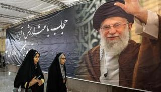 نساء إيرانيات يمررن أمام لافتة تحمل صورة خامنئي في طهران