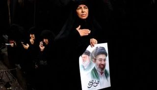 امرأة إيرانية تحمل ملصقا يحمل صورة المرشد الراحل والجديد