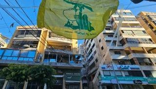 راية حزب الله أمام مبنى استهدفته غارة إسرائيلية في ضاحية بيروت الجنوبية