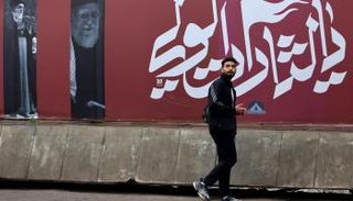 رجل يمر بجانب لافتة تصور علي خامنئي في أحد شوارع طهران