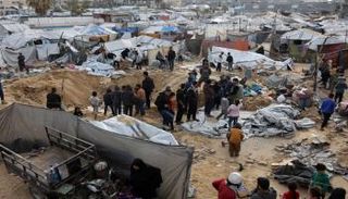 فلسطينيون يتفقدون موقع غارة إسرائيلية على مخيم خيام يؤوي نازحين في غزة